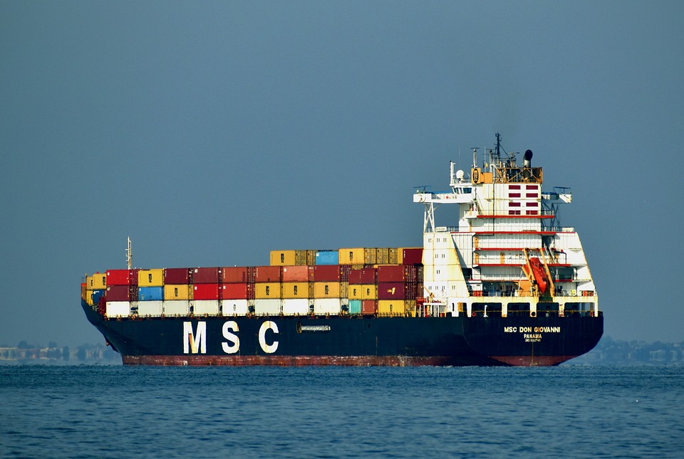 Los portacontenedores se pueden definir como buques mercantes, que con respecto a otros buques, posee un gran tamaño respecto a otros barcos comerciales, donde la eslora de suele rondar los 300 metros y con unas capacidades de hasta de 20.000 contenedores TEU.

Con respecto al manejo de estos buques, se pueden decir que estos son de difícil manejo en los puertos debido a su tamaño, lo que conlleva cierta peligrosidad tanto para el medioambiente como para las personas.

Sin embargo, estos barcos tienen una gran importancia para el funcionamiento de la vida cotidiana: ya que alrededor de 6.000 buques circulan en este momento con más de 20 millones de contenedores; esto quiere decir que el 90% de lo que consumimos a diario. Además, la capacidad de estos barcos hace que el transporte, por ejemplo, de unos pantalones ascienda a 12 céntimos y el de un teléfono móvil algo menos de 9 céntimos, un hecho que ha revolucionado el comercio internacional desde la introducción de los contenedores TEU.



Hay diferentes permisos que deben solicitar para que este tipo de buques se mueva, ya con el permiso de la autoridad, podemos distinguir tres acciones fundamentales para el atraque de portacontenedores: el practicaje, el remolcado y el amarre. Ahora veremos en qué consisten cada una de ellas. Definamos cada una de ellas:

Practicaje
El practicaje es la ayuda complementaria hasta el amarre al capitán del portacontenedores, que, aunque es un experto en navegación, puede no conocer las circunstancias locales de cada puerto. Así, un experto marino en rango de capitán mercante (práctico) estará a bordo del portacontenedores para asesorar en los movimientos del barco al capitán, aunque el práctico solo realiza su labor en calidad de asesoramiento, recayendo sobre el capitán toda la responsabilidad.

Las labores de practicaje son normalmente obligatorias para estos barcos, pues según la legislación todo barco superior a 500 GT (toneladas de registro bruto) o con mercancía peligrosa debe ser asistido. Además, en algunos puertos existe una figura denominada atalayador, cuya misión es vigilar el estado de la mar para notificar cambios de mareas, vientos, etc. y también ordenar el inicio del atraque cuando considere que las circunstancias son idóneas.



Remolcado
Los remolcadores guían al barco portacontenedores y lo empujan para facilitar las maniobras, siendo un servicio de obligado uso para estos buques mercantes. El número de remolcadores varía según el tamaño del barco, oscilando entre 1 y 4 y con una potencia que puede llegar hasta los 25.000 caballos de vapor. La dirección de estos buques depende del práctico, una figura que está presente en el puente de mando y en ocasiones también en uno de los remolcadores.

Amarre
Amarrar un barco es disponer las líneas de amarre de la embarcación de forma que estos queden fijados al muelle con seguridad, una tarea destinada en exclusiva para los amarradores. En el caso de los portacontenedores, habitualmente se trabaja contra bolardos y, cuando se trata de mercancías peligrosas, suelen valerse de sistemas de escape rápido, que optimizan los tiempos operativos, y facilitan desamarres rápidos e incluso remotos. Para el momento del contacto se requieren de los correspondientes sistemas de defensas, capacitados para absorber la energía generada y así evitan daños, tanto en los portacontenedores como en el propio muelle.

Cuando el barco se encuentra amarrado es cuando se da por finalizado el atraque y cuando comienza la carga y descarga del portacontenedores con grúas de distinto tamaño y características dependiendo del buque.

Recordemos que un buque es una embarcación marítima que posee una amplia cubierta resistente al clima y al mar, que cuenta a su vez con una buena estabilidad y puede navegar a grandes velocidades, permitiendo así que se pueda efectuar una navegación durante un periodo temporal considerable.

